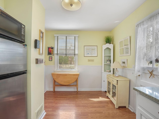 hallway with light wood-style flooring and a wainscoted wall