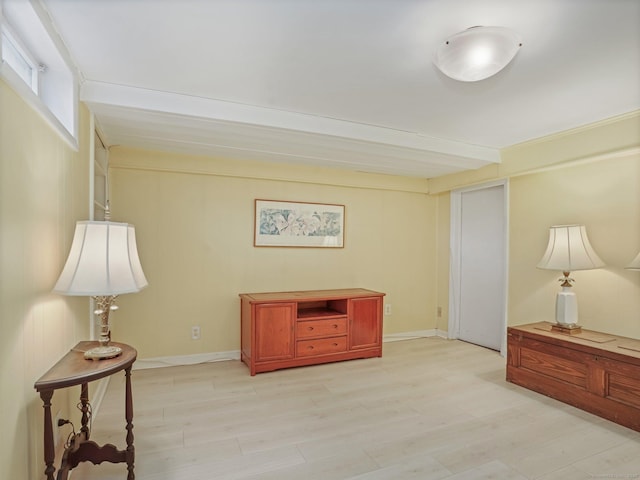 sitting room featuring beam ceiling, baseboards, and light wood-type flooring