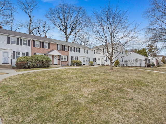 view of front of home featuring a residential view, brick siding, a chimney, and a front yard