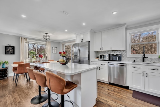 kitchen with appliances with stainless steel finishes, a kitchen island, crown molding, and a sink