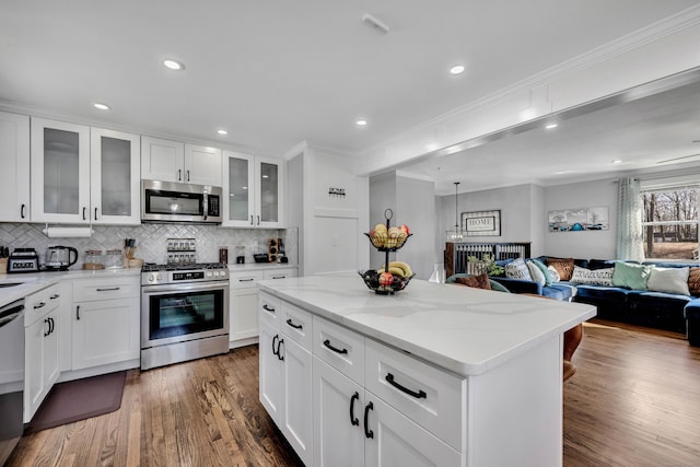 kitchen featuring backsplash, wood finished floors, open floor plan, stainless steel appliances, and crown molding