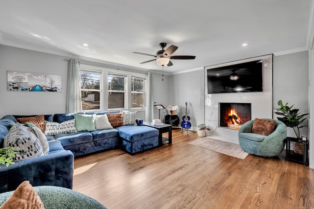 living room featuring wood finished floors, recessed lighting, a fireplace, crown molding, and ceiling fan