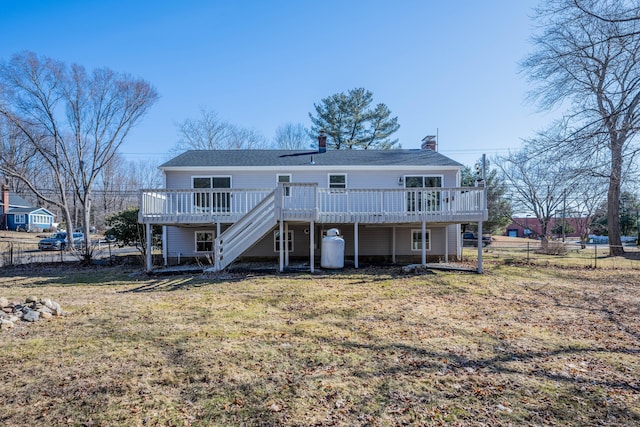 rear view of house with a yard, stairs, a deck, and fence