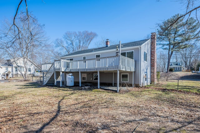 back of house featuring stairway, fence, a chimney, a deck, and a lawn