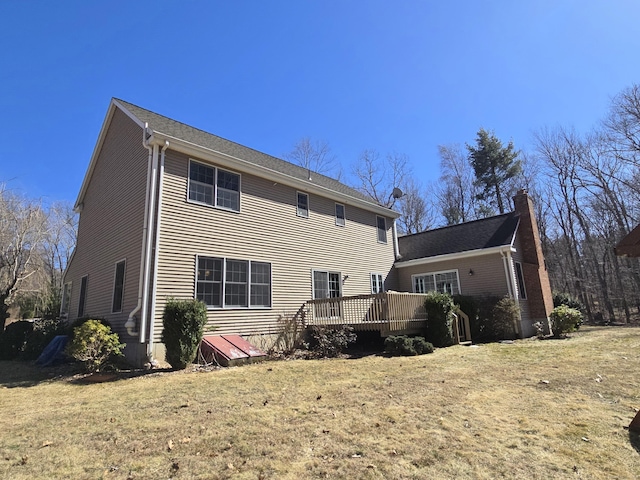 back of house with a deck, a yard, and a chimney