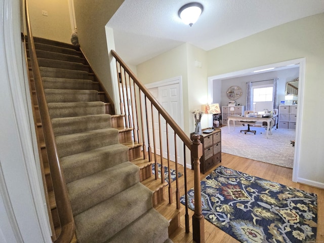 stairway featuring wood finished floors and a textured ceiling