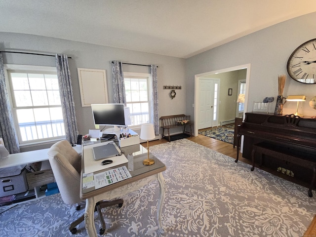 office space featuring a baseboard heating unit and wood finished floors