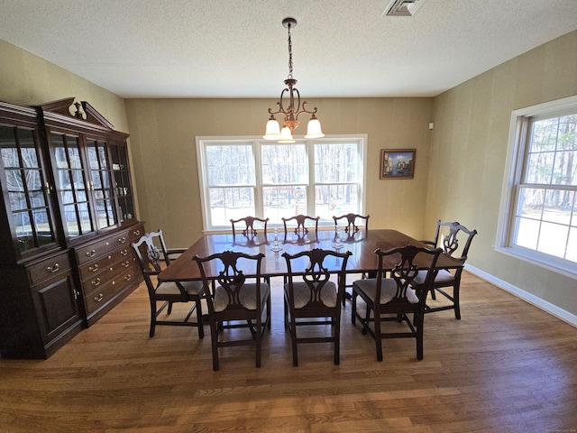 dining area with visible vents, baseboards, dark wood-type flooring, a textured ceiling, and a chandelier