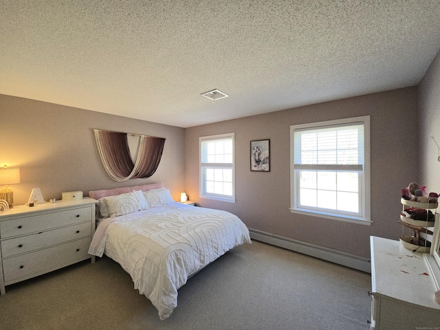 bedroom featuring dark carpet, visible vents, baseboard heating, and a textured ceiling