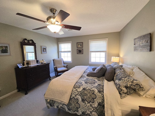 bedroom with a ceiling fan, visible vents, carpet, baseboards, and a textured ceiling