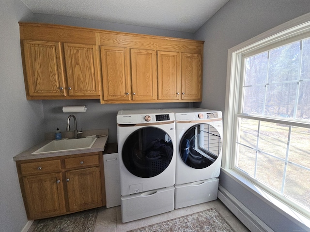 laundry area featuring a healthy amount of sunlight, washing machine and dryer, light tile patterned flooring, cabinet space, and a sink