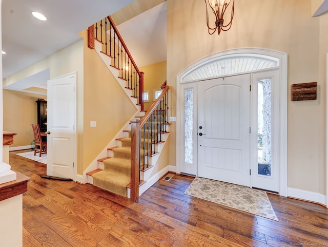 entryway with stairway, a towering ceiling, baseboards, and hardwood / wood-style floors