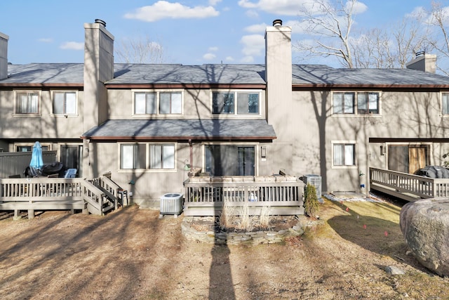 back of house with a wooden deck, cooling unit, and a chimney