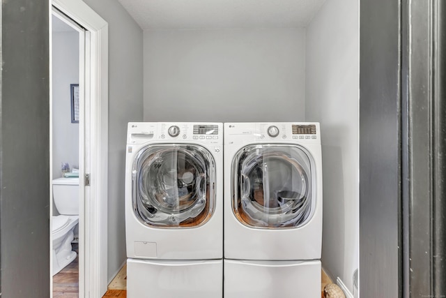 washroom with laundry area, wood finished floors, and washing machine and clothes dryer