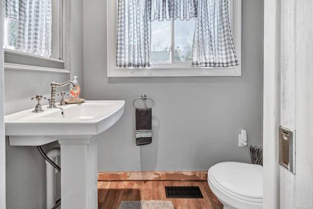 bathroom with toilet, wood finished floors, and visible vents