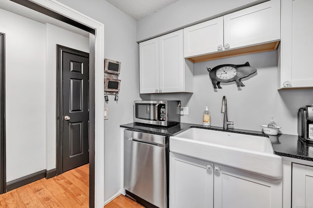 kitchen featuring a sink, stainless steel appliances, light wood-style flooring, and white cabinetry