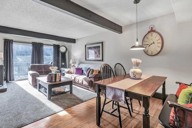 dining room featuring beamed ceiling, wood-type flooring, and a textured ceiling