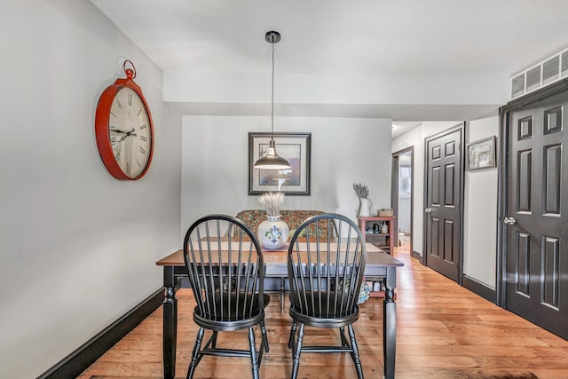 dining area with light wood-style flooring, baseboards, and visible vents