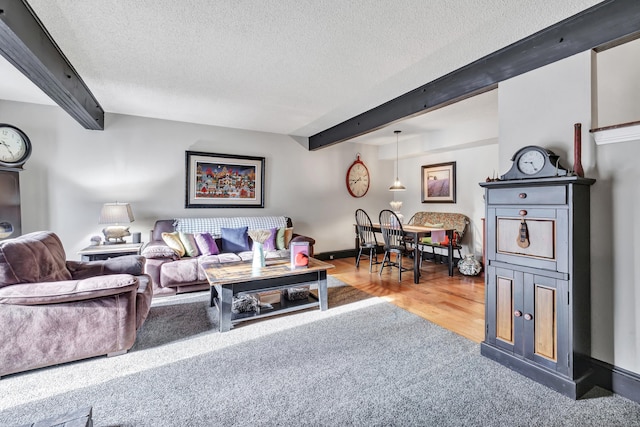 living area with beamed ceiling, wood finished floors, baseboards, and a textured ceiling