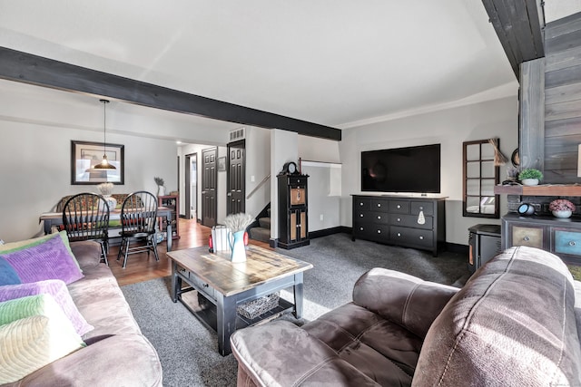 living area featuring visible vents, beamed ceiling, wood finished floors, stairway, and baseboards