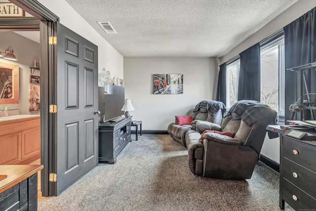 living area with visible vents, carpet floors, a textured ceiling, and baseboards