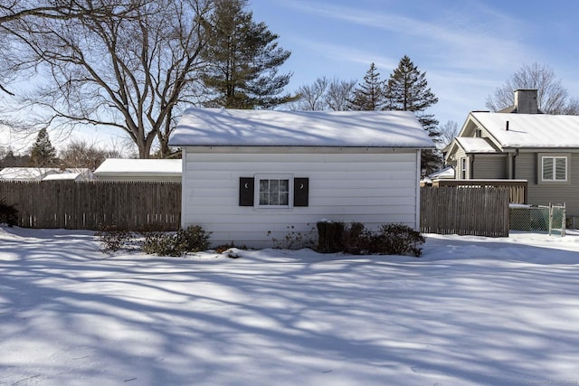 snow covered structure featuring an outbuilding and fence