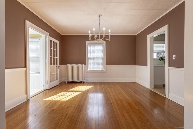 unfurnished dining area with a wealth of natural light, radiator, and hardwood / wood-style flooring