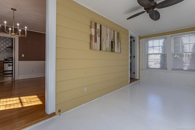 unfurnished room featuring a wainscoted wall and ceiling fan with notable chandelier