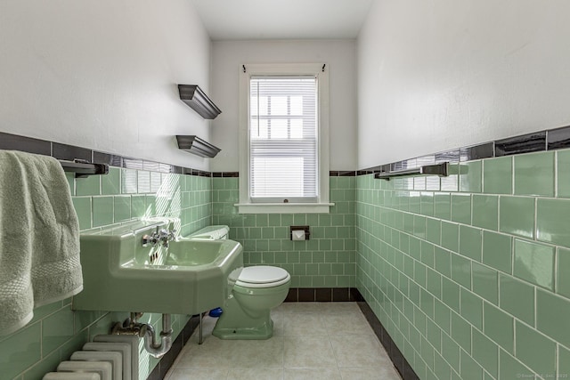 bathroom featuring tile patterned floors, radiator, toilet, and a wainscoted wall