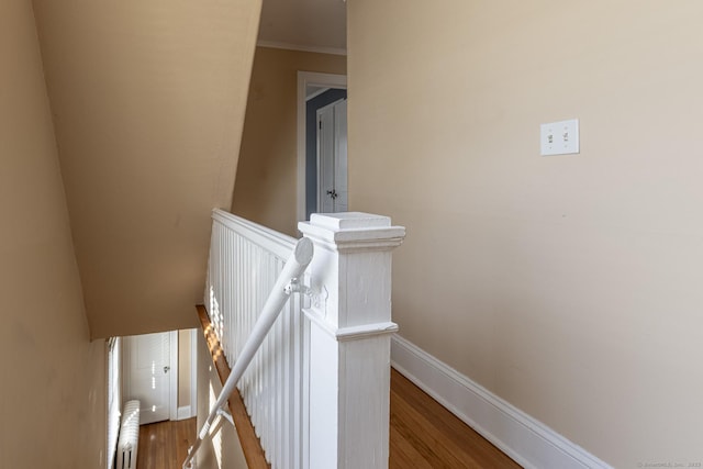 stairs featuring baseboards, wood finished floors, and crown molding