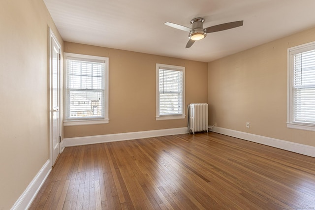 unfurnished room with radiator, a ceiling fan, baseboards, and hardwood / wood-style floors