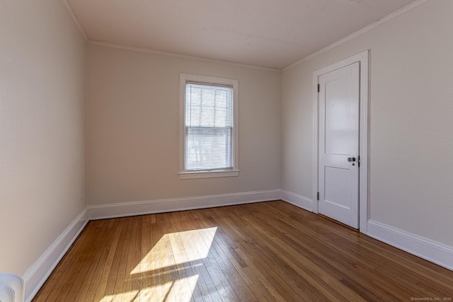 empty room with crown molding, baseboards, and hardwood / wood-style floors