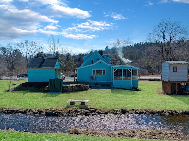 rear view of house with a yard, an outbuilding, and a shed