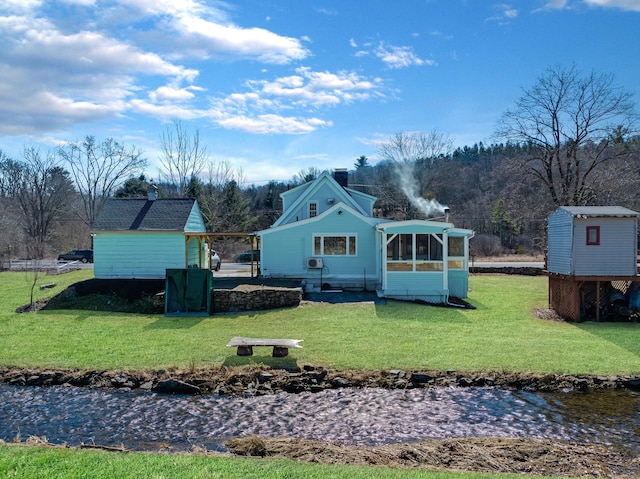 back of house with a chimney, a storage shed, and a yard