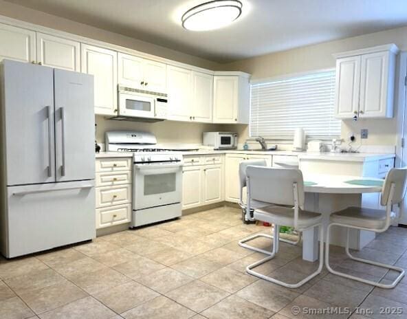 kitchen featuring white appliances, white cabinets, light tile patterned flooring, and light countertops