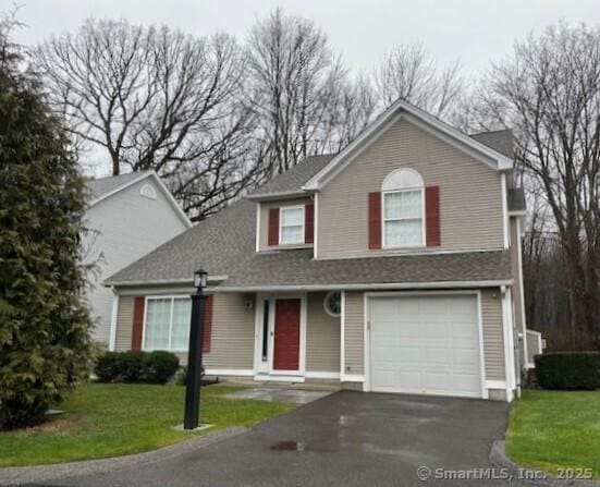 traditional home featuring a front lawn, an attached garage, and driveway