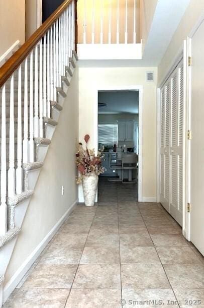 stairway featuring tile patterned floors, visible vents, baseboards, and a towering ceiling