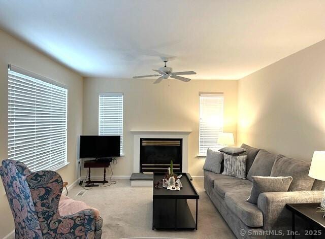 living area with a ceiling fan, baseboards, carpet, and a fireplace