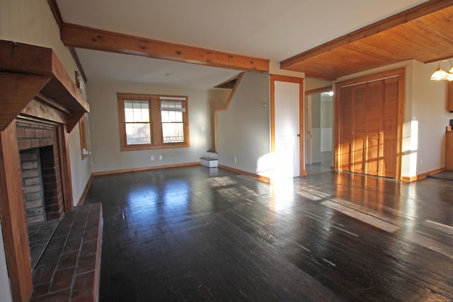 unfurnished living room with beamed ceiling, wood-type flooring, baseboards, and a fireplace