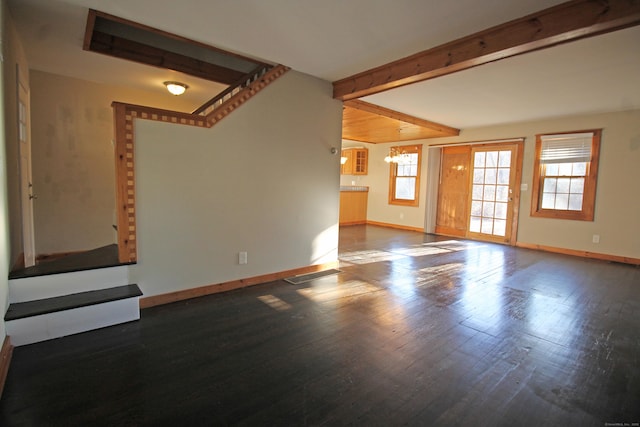 unfurnished living room featuring wood finished floors, visible vents, baseboards, lofted ceiling with beams, and a chandelier