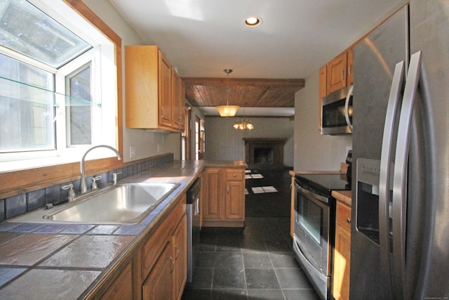 kitchen featuring a sink, recessed lighting, tile countertops, appliances with stainless steel finishes, and hanging light fixtures