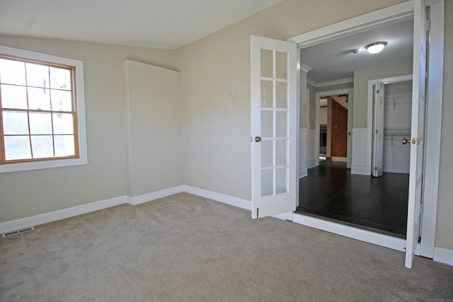 empty room with carpet, visible vents, and baseboards