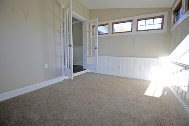 carpeted empty room featuring vaulted ceiling and baseboards