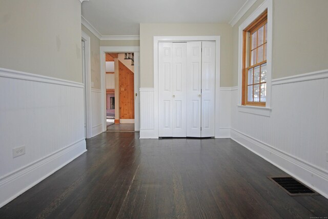 unfurnished bedroom featuring a wainscoted wall, wood finished floors, visible vents, and a closet