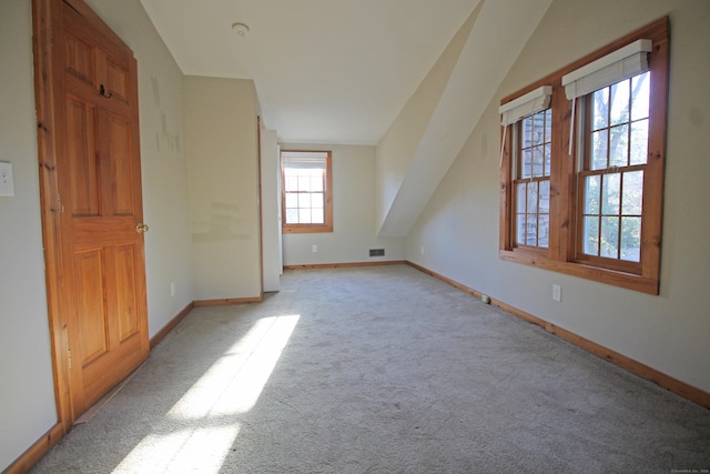 bonus room featuring lofted ceiling, baseboards, visible vents, and light carpet