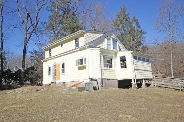 back of house with central air condition unit, entry steps, a chimney, and fence