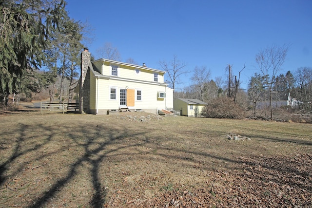 back of property featuring a lawn, entry steps, and a chimney