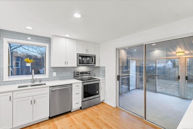 kitchen featuring backsplash, stainless steel appliances, light countertops, and a sink