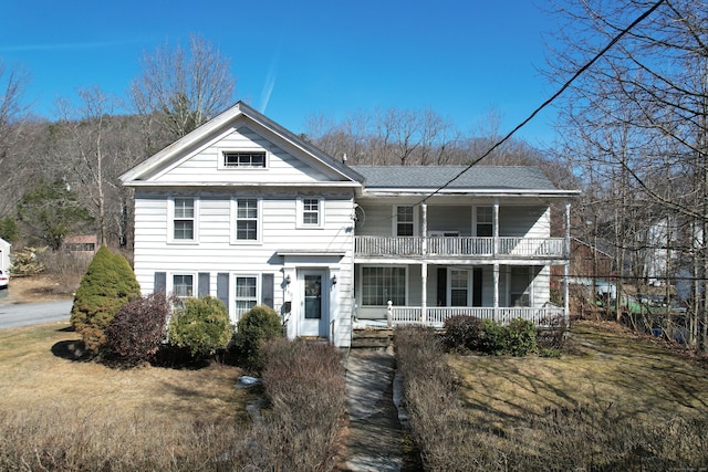 view of front of house featuring a porch, a balcony, and a front yard