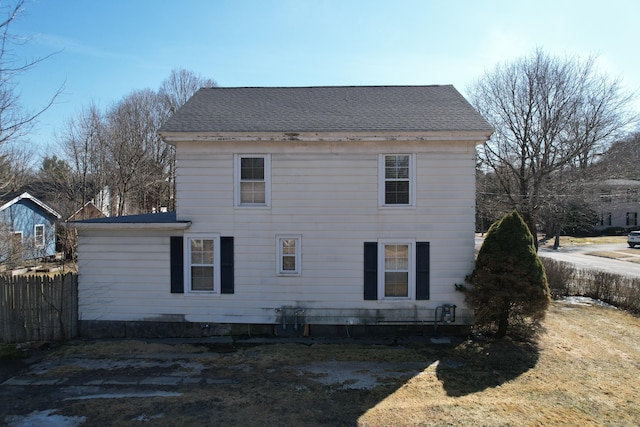 rear view of property featuring roof with shingles and fence